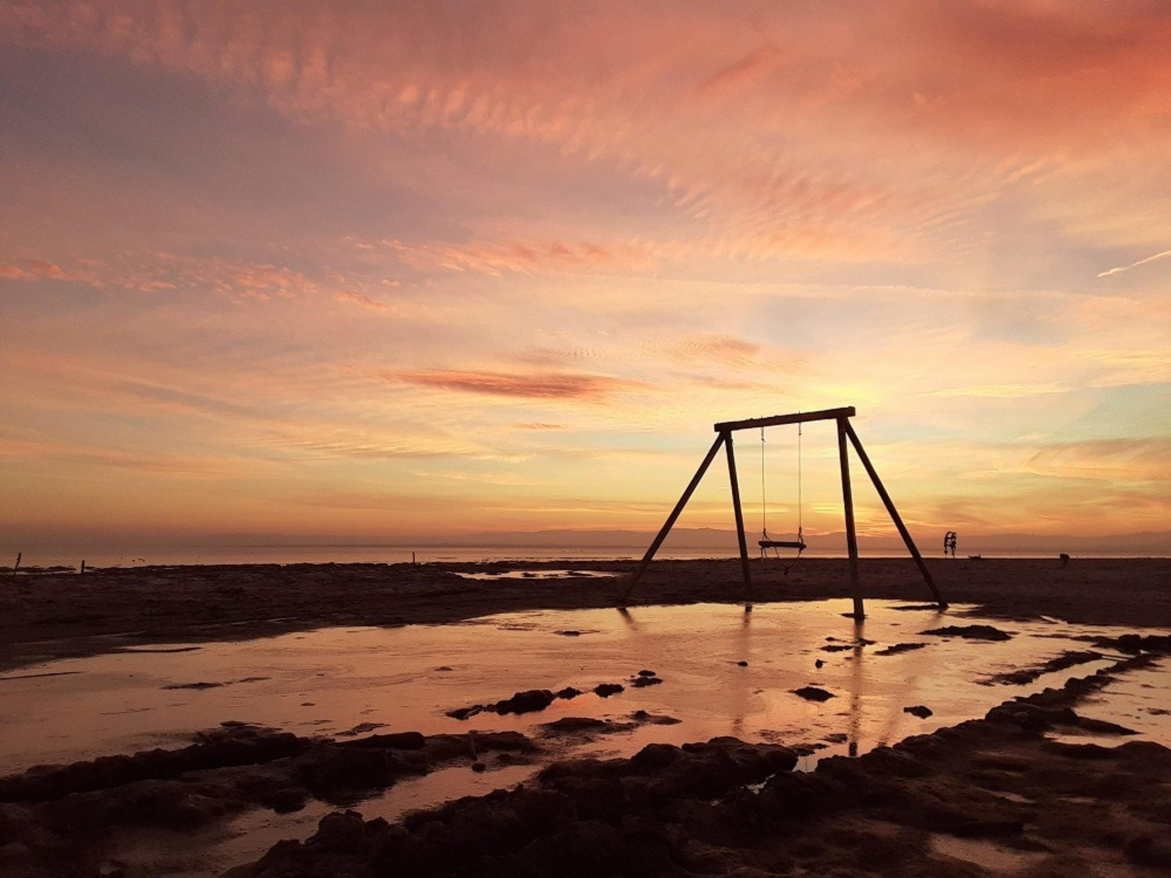 Beach with swing at sunset