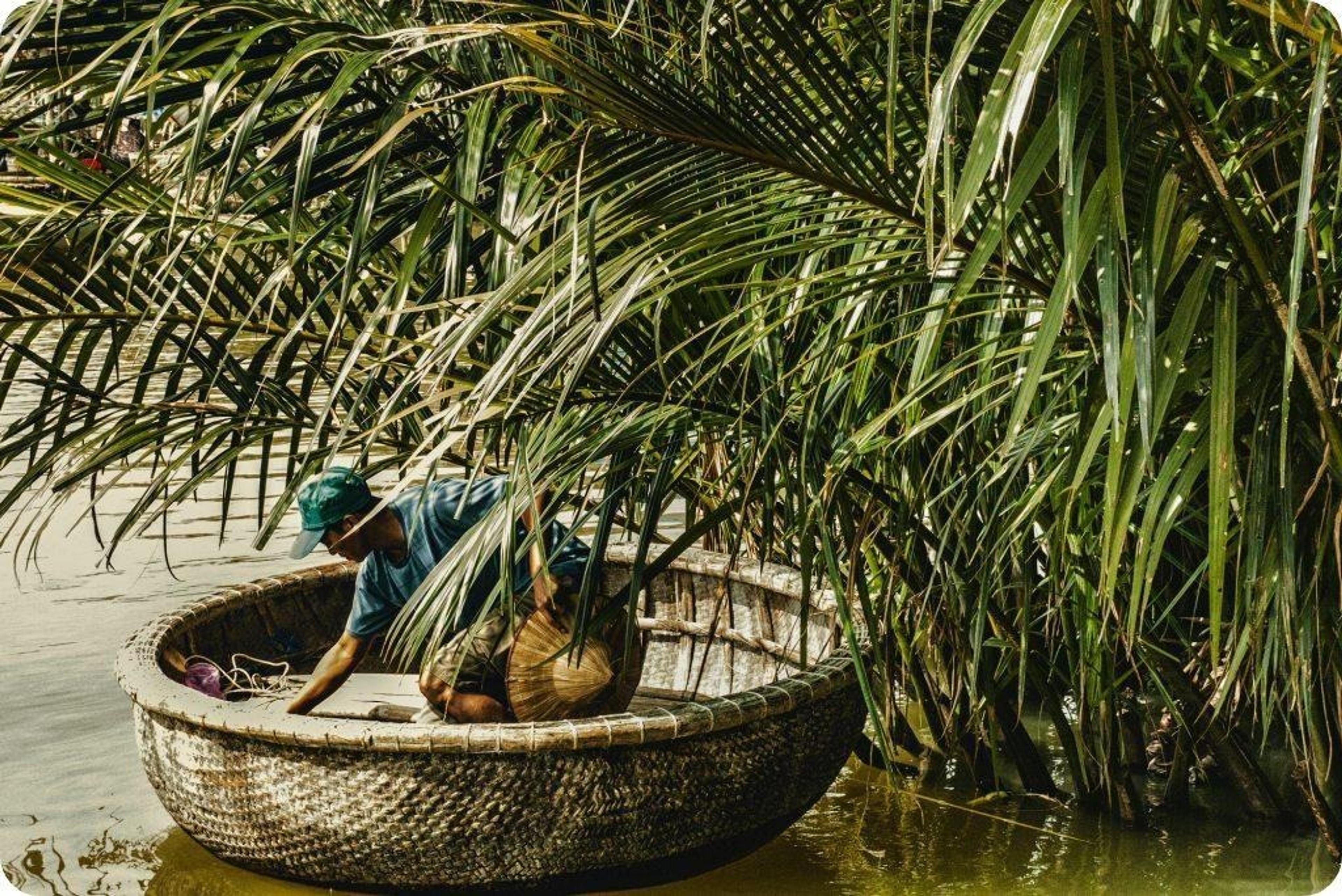 Man in basket boat surrounded by plants