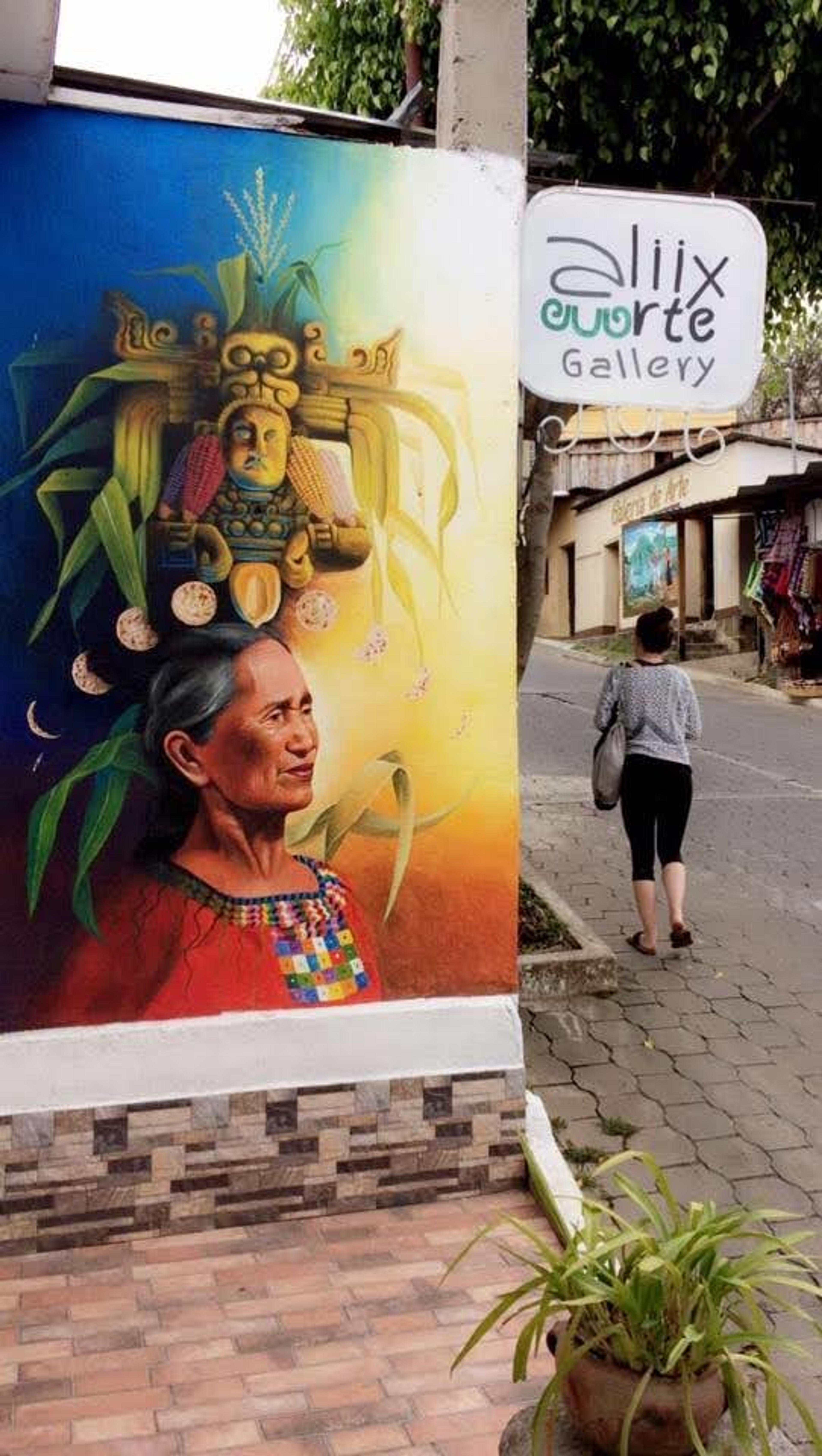Colourful Maya art on a wall beside a cobbled street