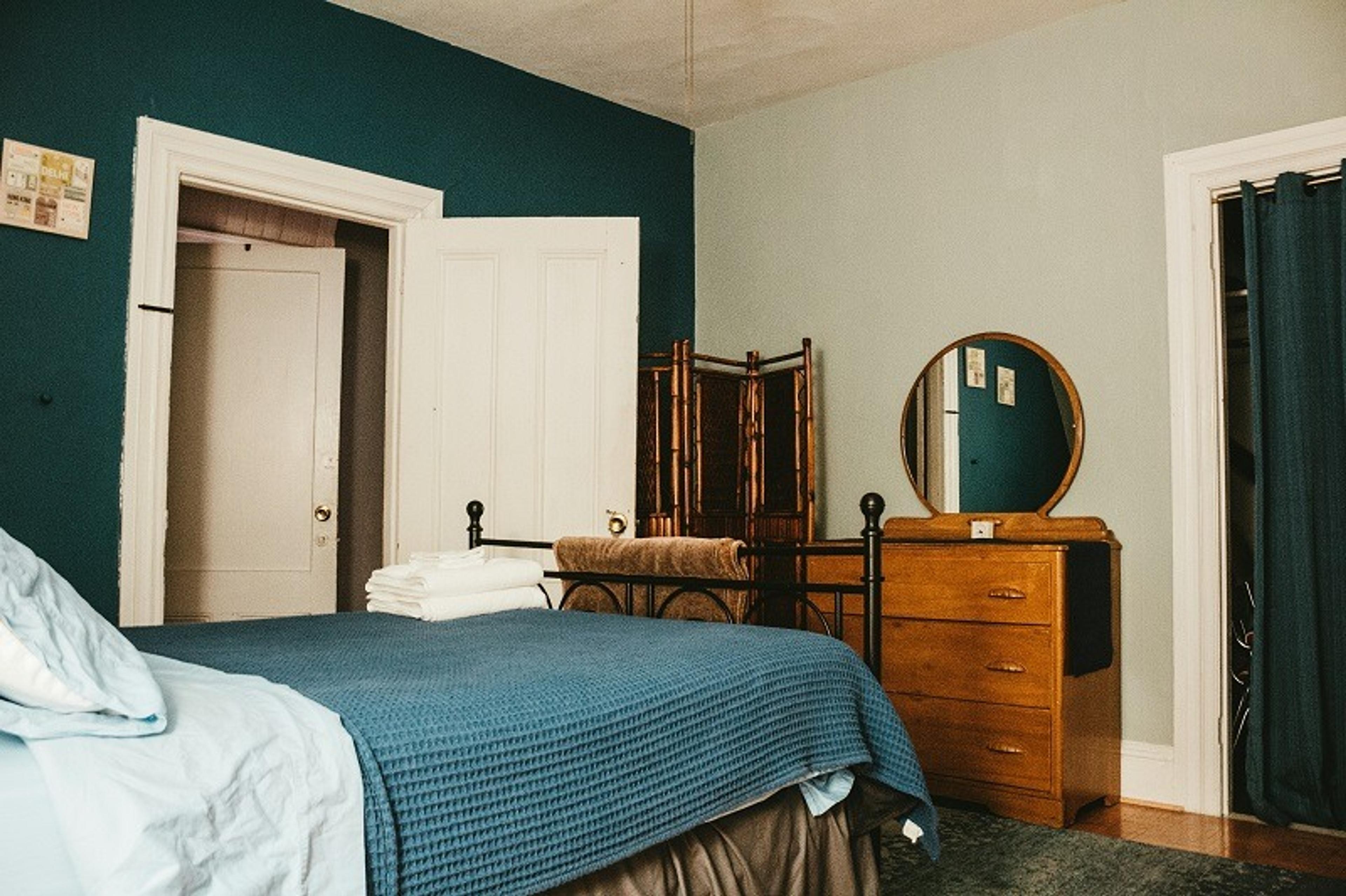 Bedroom with green walls, a bed, round mirror and drawers