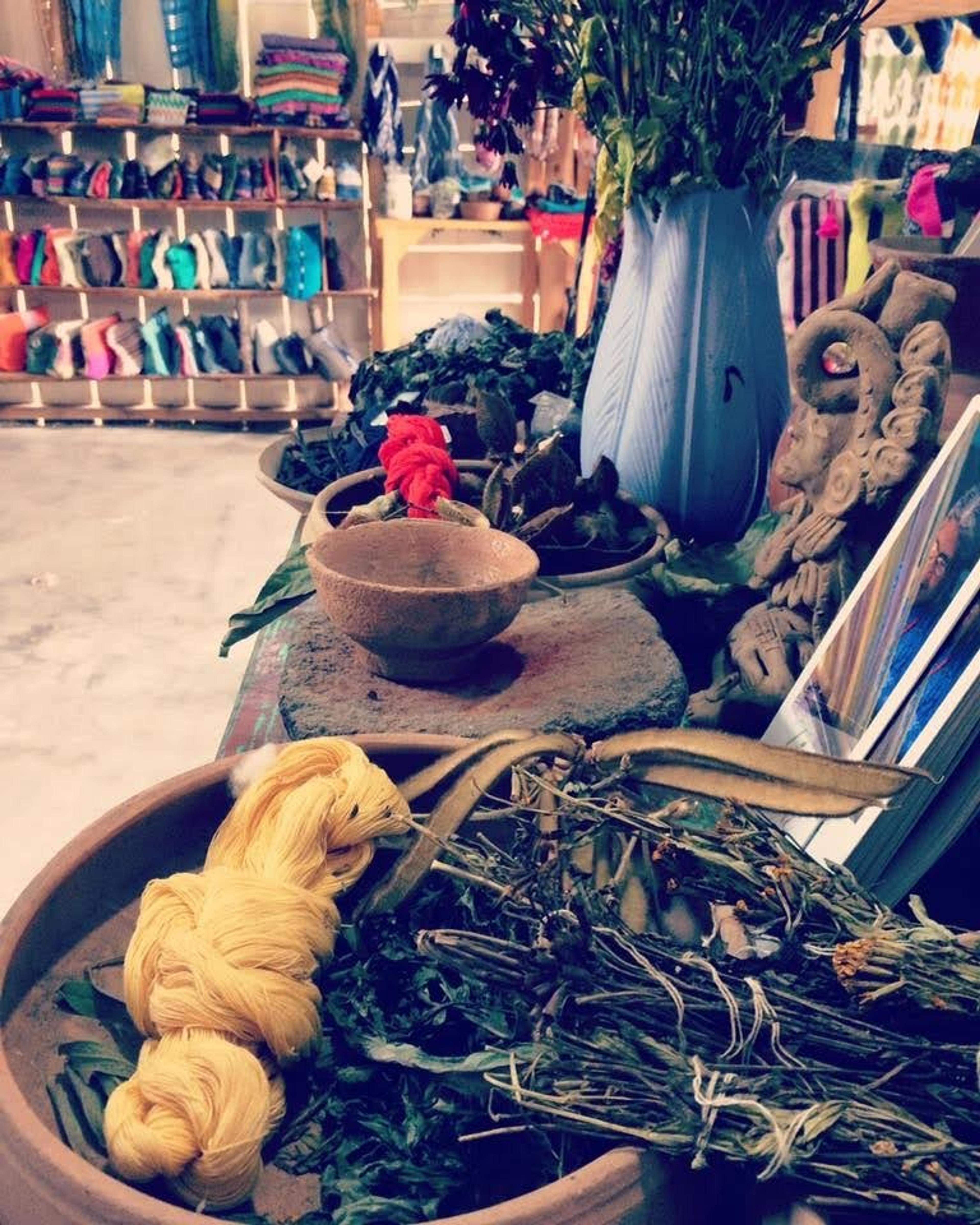 Fabrics being dyed in wooden bowls full of leaves